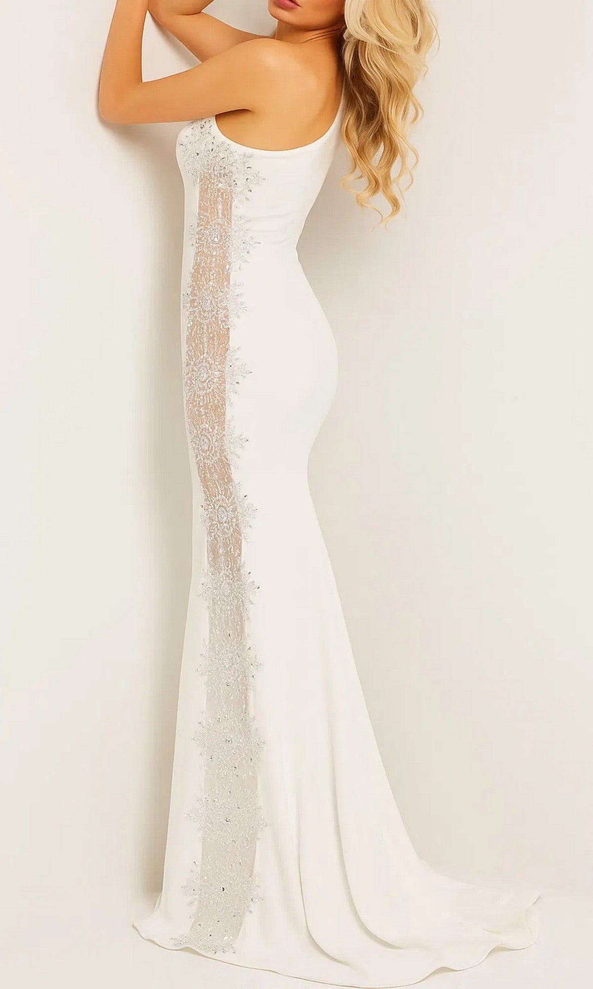 A woman wears the Long Prom Dress: Jovani 22500 in white, featuring side lace detailing and stretch jersey fabric, standing against a plain light background.